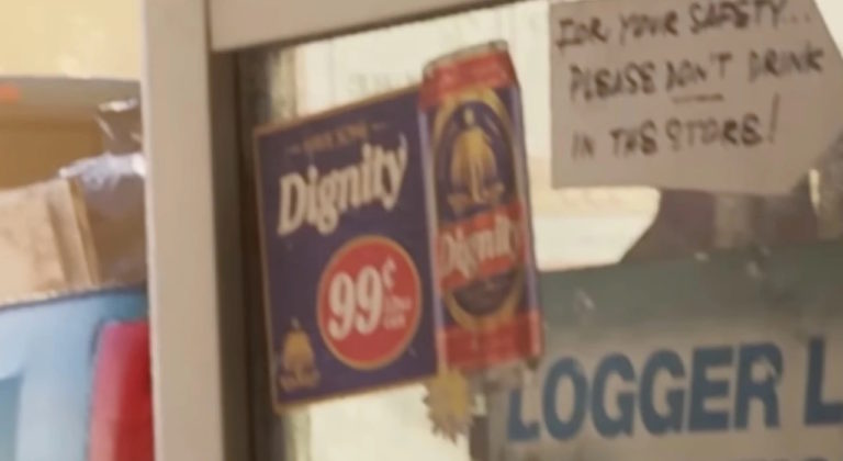 Рекламный плакат напитка Dignity с ценой 99 центов и банкой, рядом рукописная табличка с просьбой не пить в магазине для безопасности.