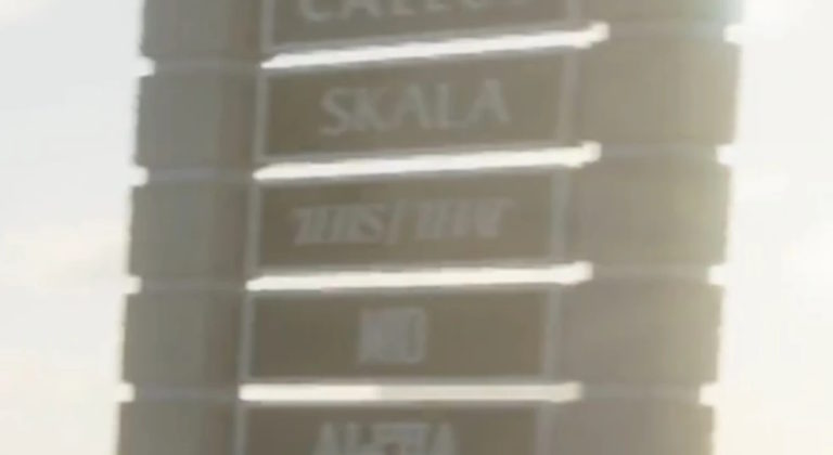 Таблички с названиями: CALLEO, SKALA, ALFA, а также надпись, похожая на ZHIS/THW, расположены вертикально на стене здания, освещённой солнцем.