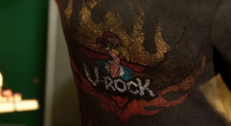 Татуировка с изображением петуха, окружённого пламенем, и надписью V-ROCK на фоне сердца и красных языков пламени. Яркие цвета и агрессивный стиль подчеркивают рок-тематику и бунтарский характер изображения. Татуировка выполнена на коже, детали проработаны с акцентом на динамику и энергетику. Ключевая фраза: татуировка V-ROCK.