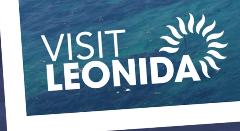Рекламный плакат с надписью VISIT LEONIDA на фоне морской воды, рядом стилизованное изображение солнца. Ключевая фраза: VISIT LEONIDA.