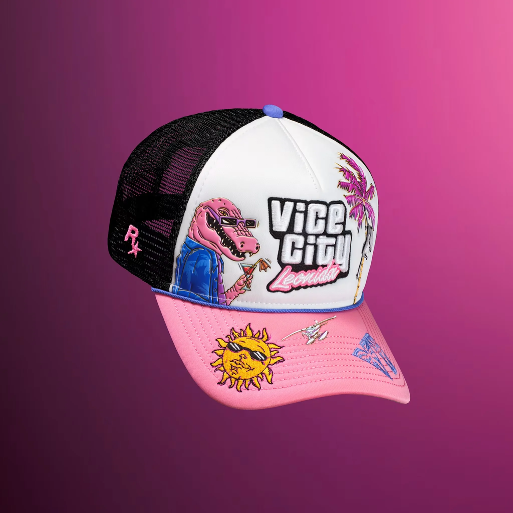 Стильная кепка Vice City Leonida с яркими вышивками и оригинальным принтом. Кепка с сетчатой черной задней частью и ярким дизайном спереди: надпись Vice City Leonida, розовый крокодил в очках, пальма, вышитое солнце и самолет на розовом козырьке. Фон — градиент от фиолетового к розовому.